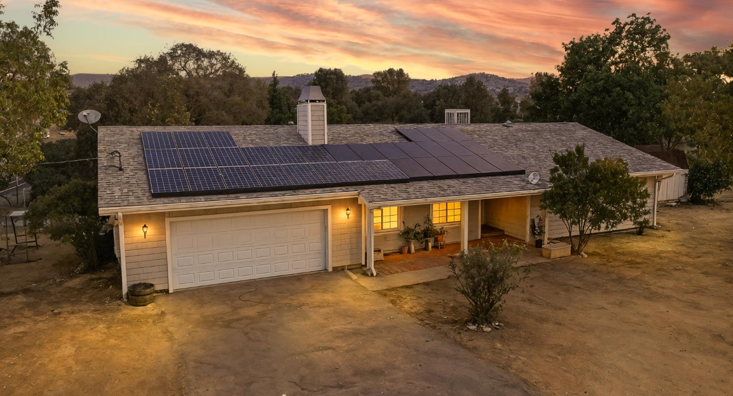 a view of house with backyard and trees in the background