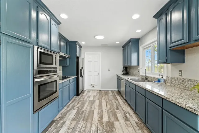 a kitchen with granite countertop stainless steel appliances sink microwave and cabinets