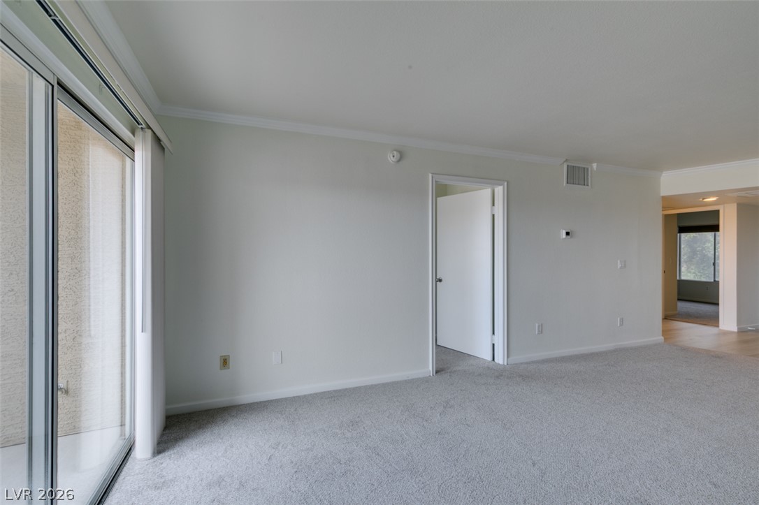 8070 West Russell Road, Unit 2026 Las Vegas, NV 89113 - Photo 24 of 41 A spacious living area features soft carpeting, crown molding, and abundant natural light from sliding glass doors.