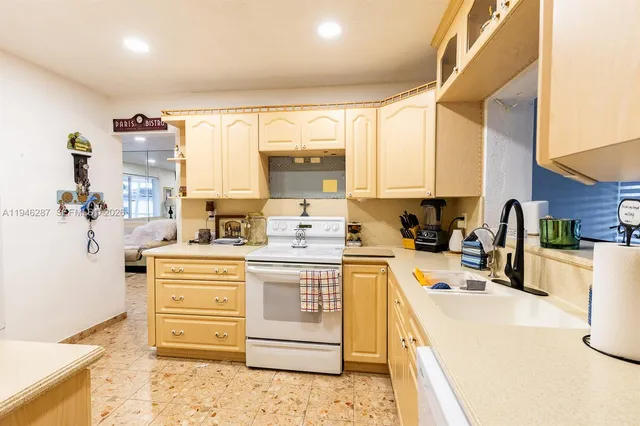 a kitchen with stainless steel appliances kitchen island granite countertop a stove a sink dishwasher and white cabinets with wooden floor