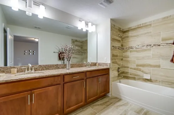 a bathroom with a bathtub a double vanity sink and a mirror