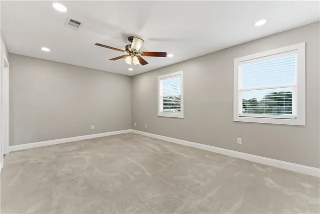 an empty room with windows and fan