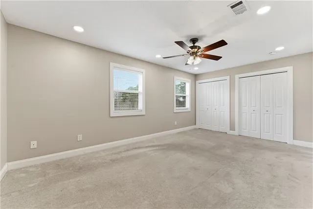 an empty room with windows and ceiling fan
