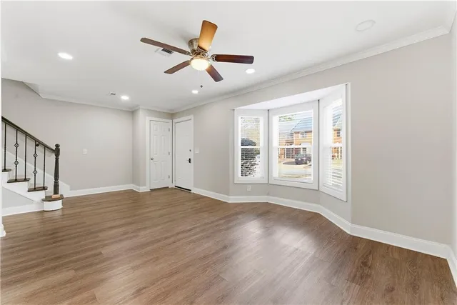 a view of an empty room with wooden floor and a window
