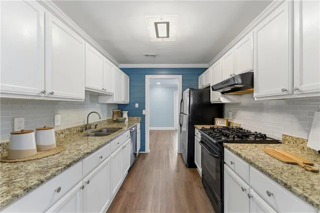 a kitchen with granite countertop stainless steel appliances a stove a refrigerator a sink and dishwasher with wooden cabinets