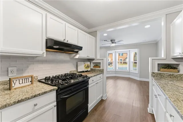 a kitchen with granite countertop stainless steel appliances a stove cabinets and wooden floor