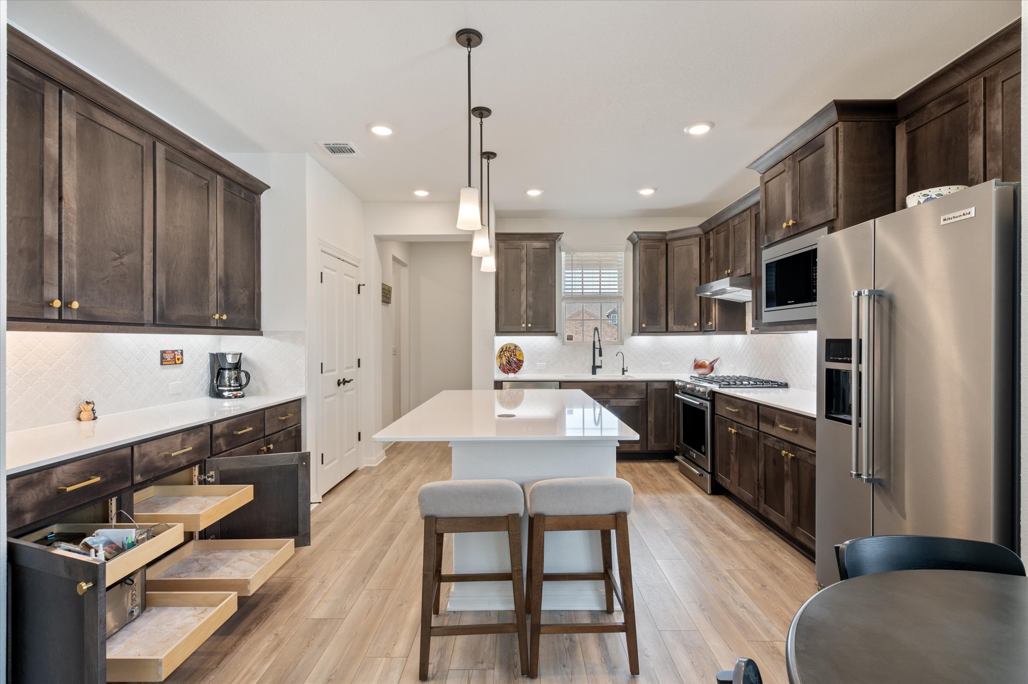 112 Clay Hl Street Georgetown, TX 78633 - Photo 10 of 29 a large kitchen with stainless steel appliances kitchen island granite countertop a refrigerator a sink dishwasher a dining table and chairs with wooden floor