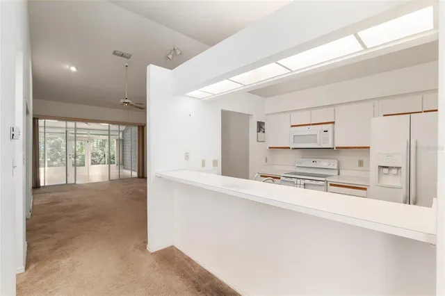 a large white kitchen with kitchen island a sink stainless steel appliances and cabinets