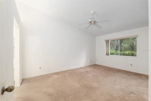 an empty room with a window and ceiling fan