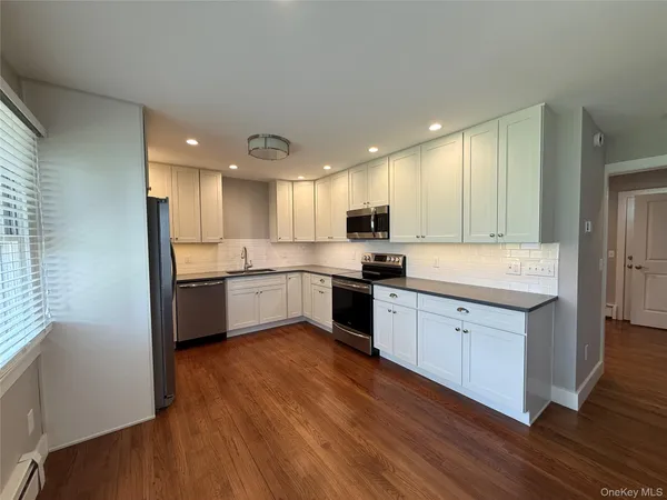 a large kitchen with a center island wooden floor stainless steel appliances and cabinets
