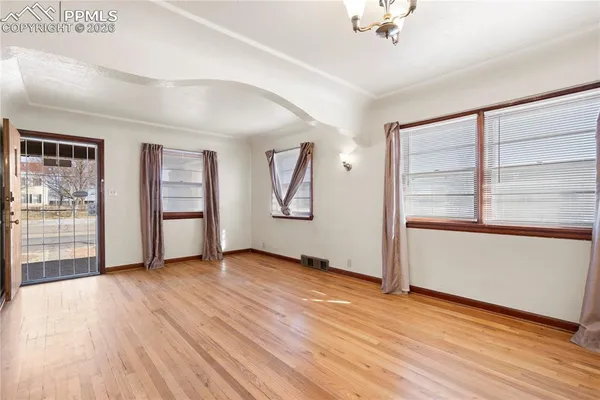 an empty room with wooden floor and windows