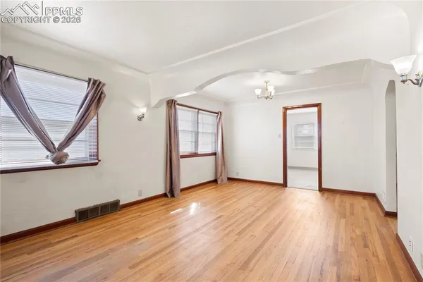 a view of an empty room with wooden floor and a window