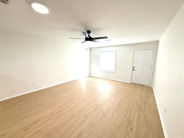 an empty room with wooden floor and ceiling fan