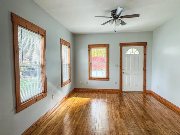 a view of empty room with wooden floor and fan