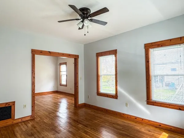 a view of an empty room with a window and wooden floor