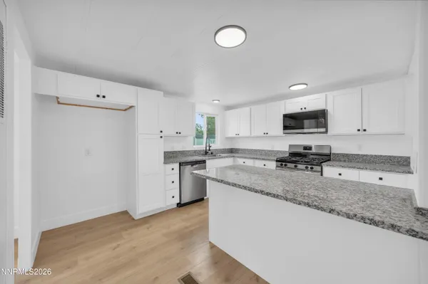 a kitchen with granite countertop a sink a stove a refrigerator a center island and cabinets