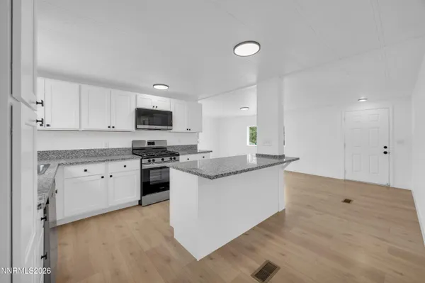 a kitchen with granite countertop white cabinets and stainless steel appliances