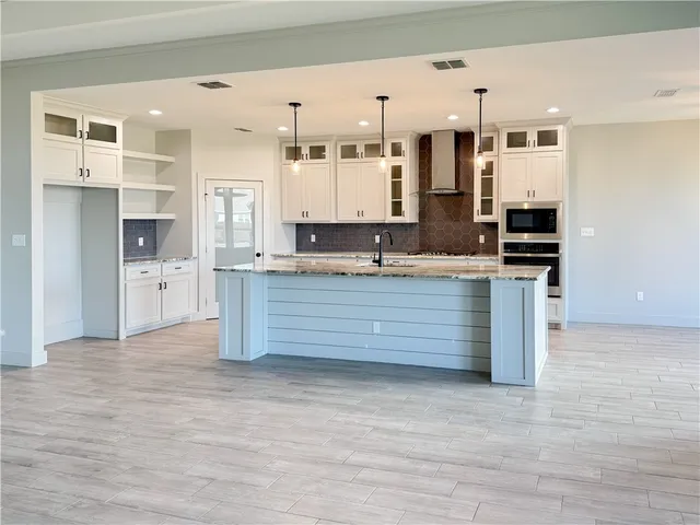 a kitchen with granite countertop a stove oven and white cabinets
