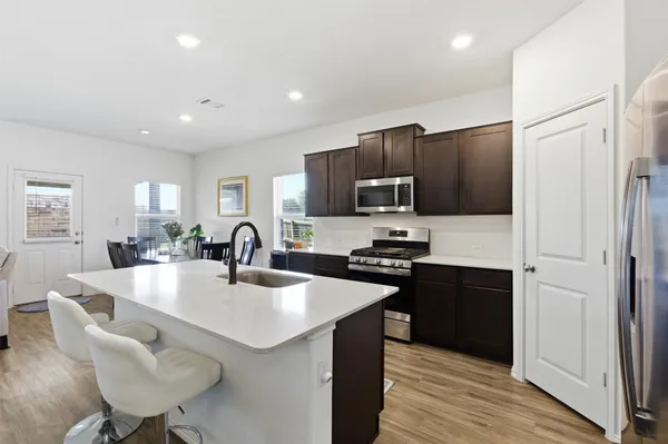 a kitchen with stainless steel appliances granite countertop a sink a stove a refrigerator and island