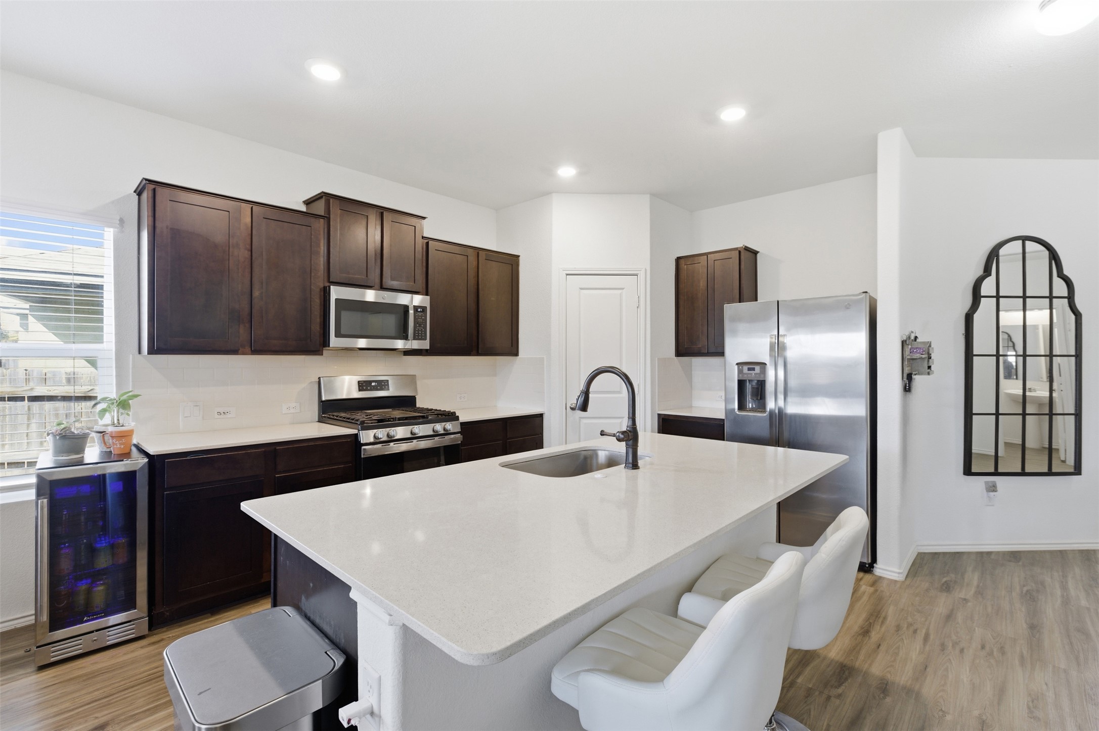 832 Mallow Road Leander, TX 78641 - Photo 4 of 29 Kitchen with stainless steel appliances, light wood-style flooring, beverage cooler, dark wood finish cabinets, and recessed lighting