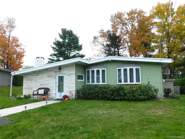 a view of a house with a yard plants and large tree