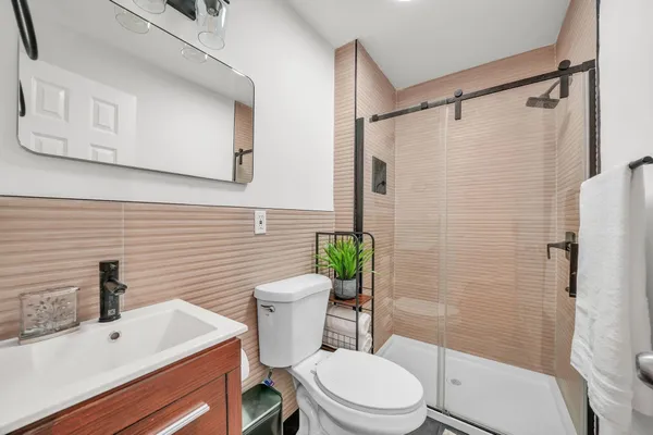 a bathroom with a sink a toilet a glass door a shower and a mirror