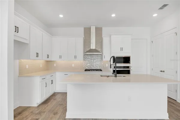 a kitchen with stainless steel appliances a sink a stove a refrigerator a center island and cabinets