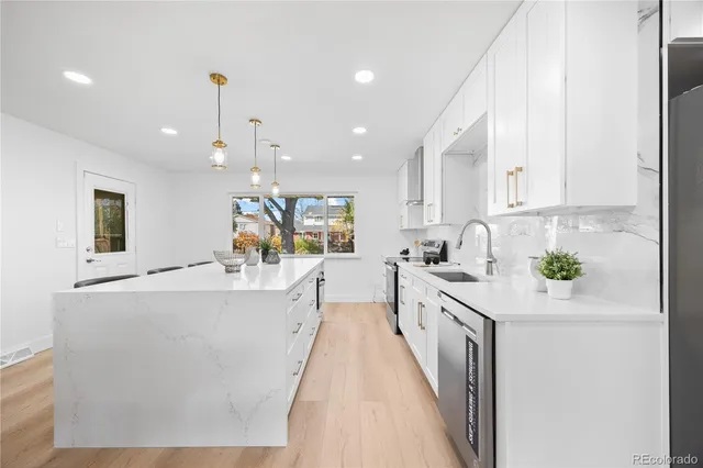 a large kitchen with stainless steel appliances a large counter top a stove a chimney a sink and a refrigerator