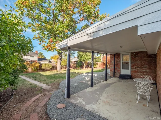 a patio with table and chairs and potted plants