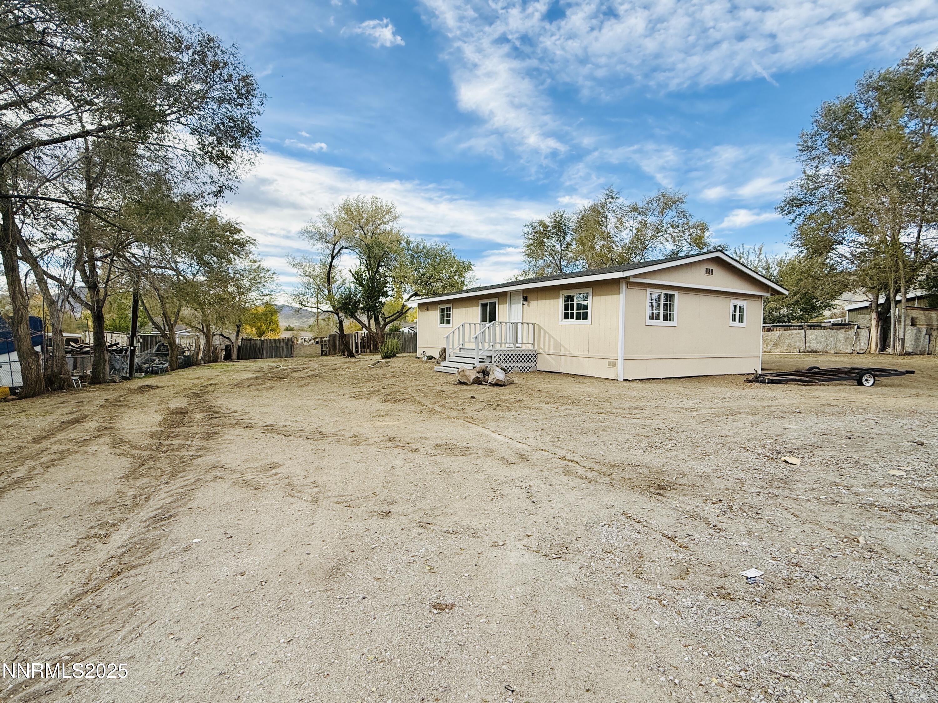a view of house with yard and trees in the background
