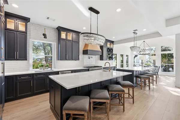 a kitchen with stainless steel appliances granite countertop a stove a sink dishwasher a dining table and chairs with wooden floor