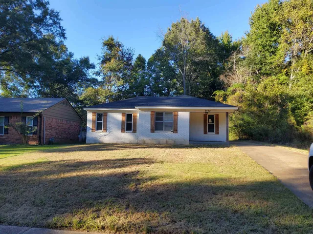 a front view of house with yard and trees in the background