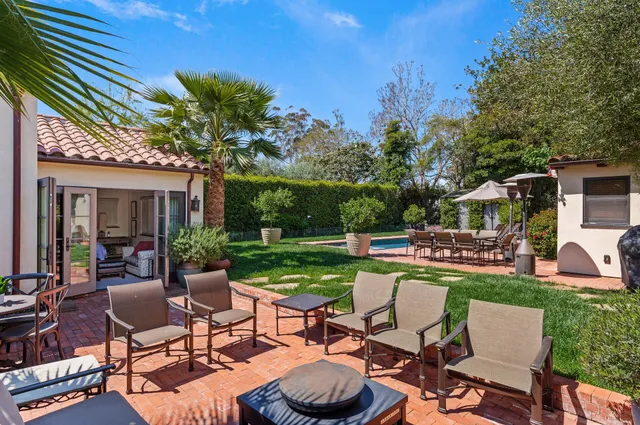 a view of a patio with table and chairs potted plants and large tree