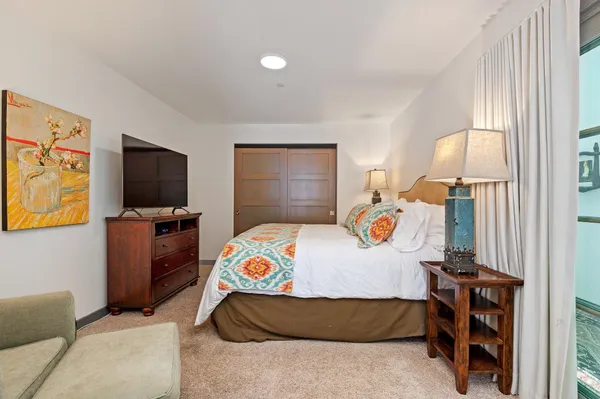 a bedroom with a bed and a flat tv screen on dresser