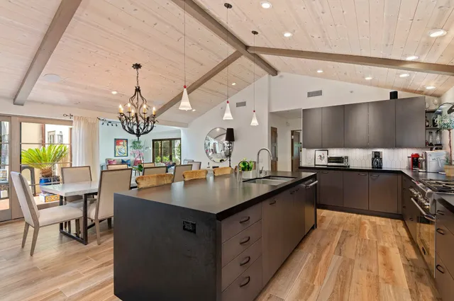 a large kitchen with stainless steel appliances a large counter top a stove and a chandelier