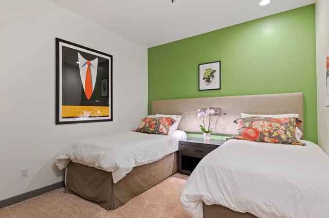 a bedroom with 2 bed and a painting on the wall