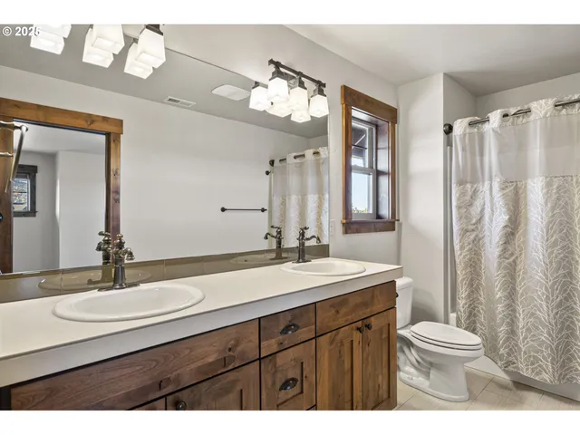 a bathroom with a sink a toilet a mirror a window and vanity