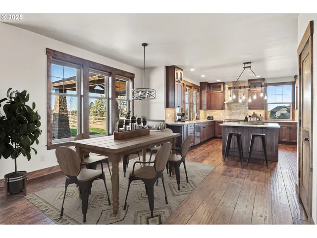 a dining room with stainless steel appliances kitchen island granite countertop a table chairs and a view of living room