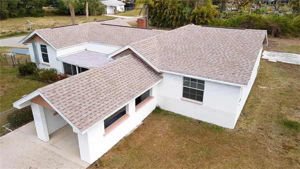 an aerial view of residential houses with yard and trees in the background