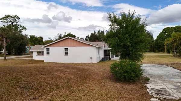 a view of a house with a yard and large trees