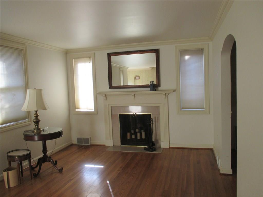 Living room with exposed wood floors, ceiling moulding, extra trim around the windows, archway!