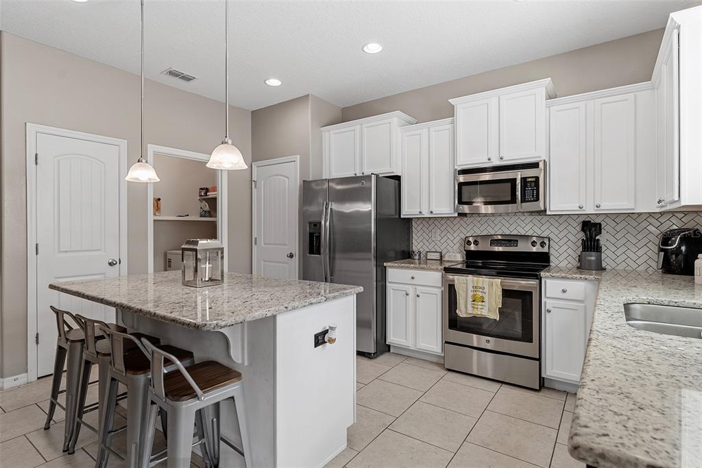 3523 Clay Brick Road St. Cloud, FL 34773 - Photo 18 of 62 a kitchen with stainless steel appliances granite countertop a stove a sink a microwave a refrigerator and white cabinets