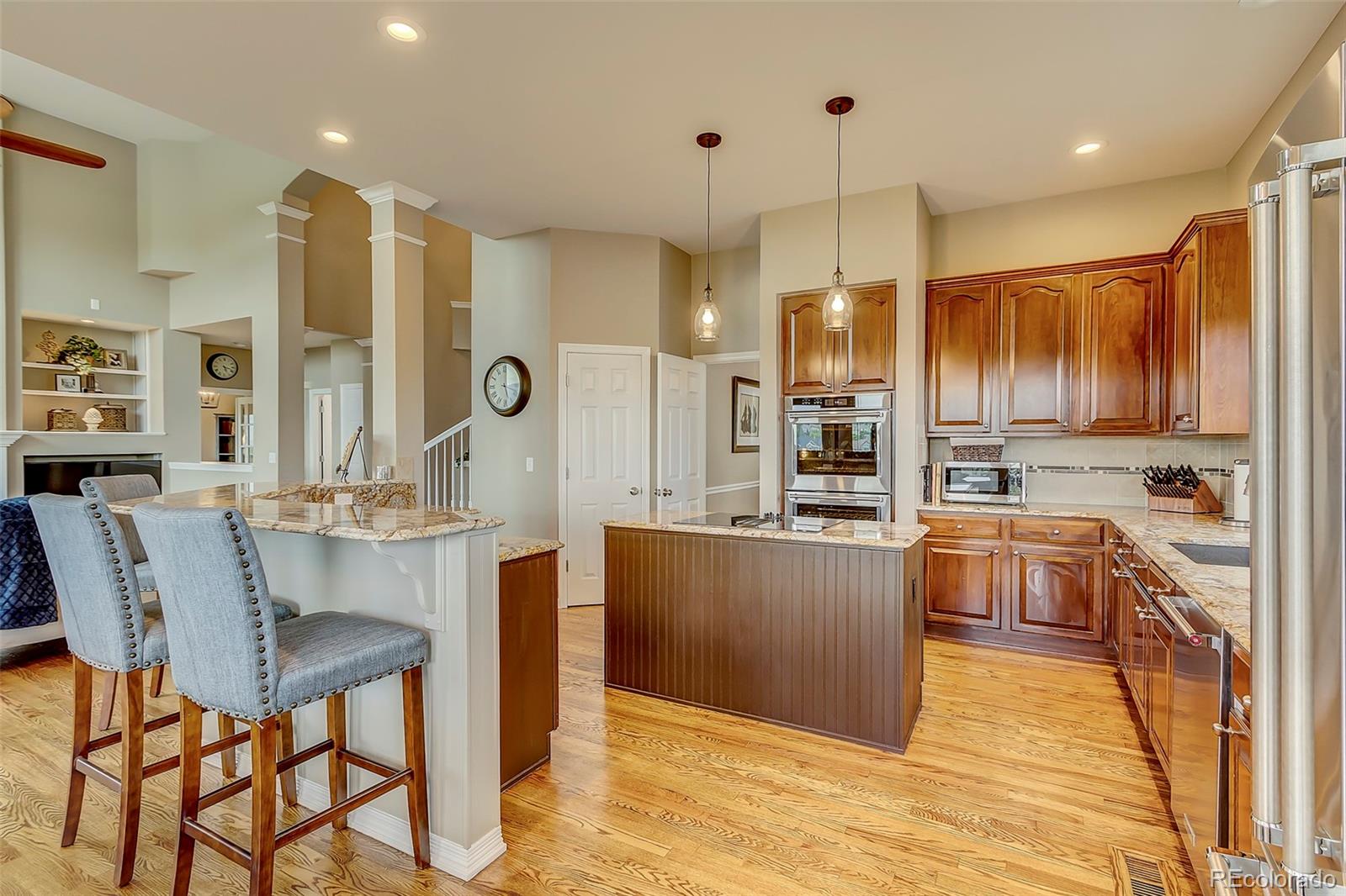 456 West Angus Way Highlands Ranch, CO 80129 - Photo 11 of 40 a kitchen with stainless steel appliances kitchen island granite countertop a table chairs and a refrigerator