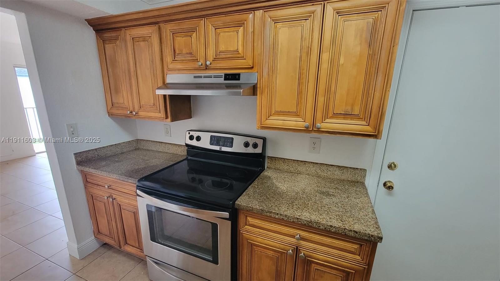 7232 Southwest 94th Place, Unit E7 Miami, FL 33173 - Photo 5 of 10 a kitchen with granite countertop cabinets stove and microwave
