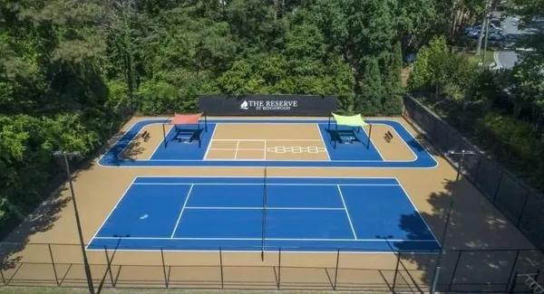 a view of a tennis ground with large trees