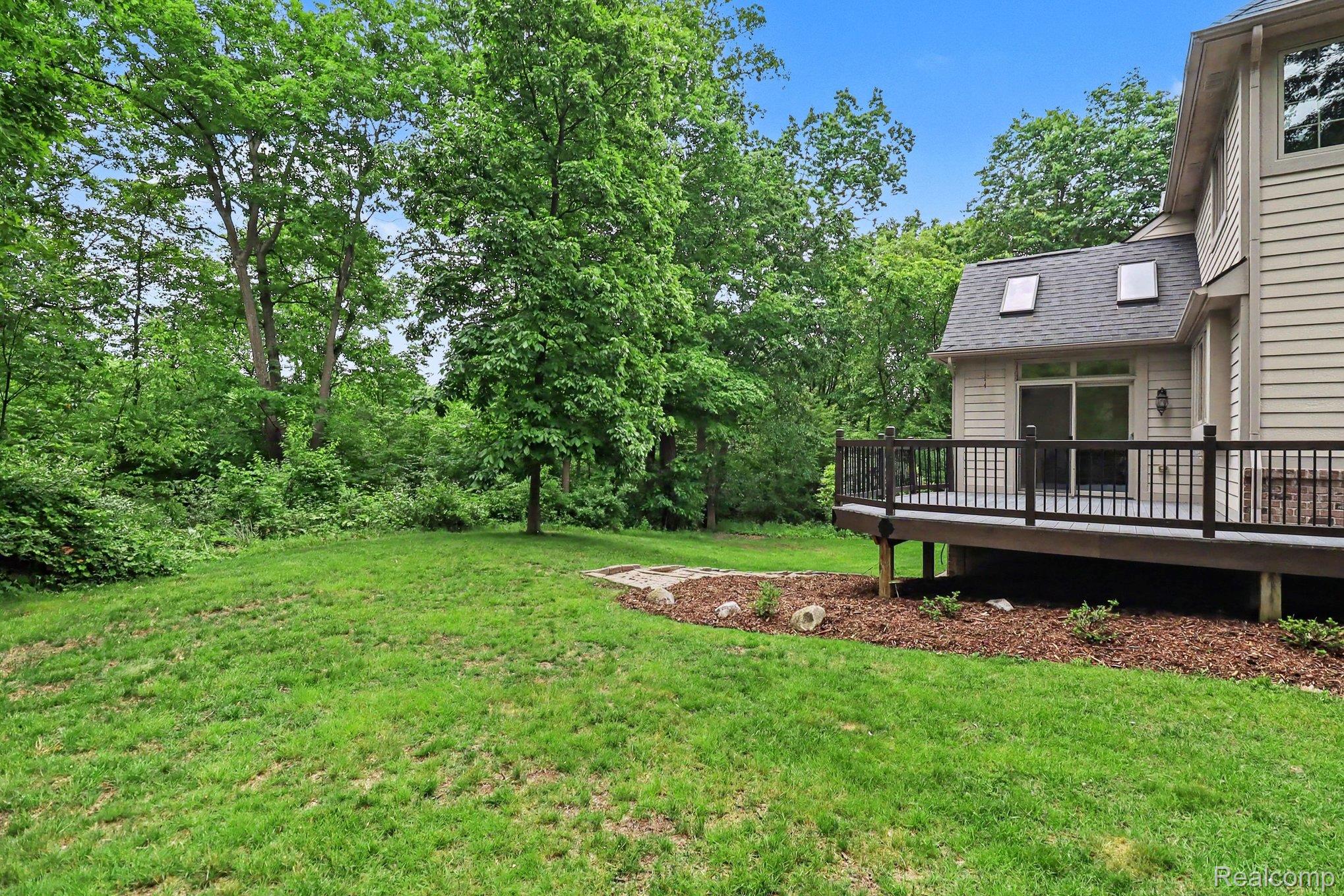 10490 Deer Ridge Trail Holly, MI 48442 - Photo 53 of 56 Expansive rear yard featuring a wooden deck with dark railings, a sliding glass door, and two skylights