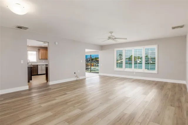 an empty room with wooden floor chandelier and windows