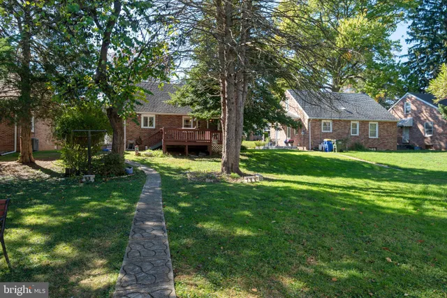 a backyard of a house with garden and tall trees