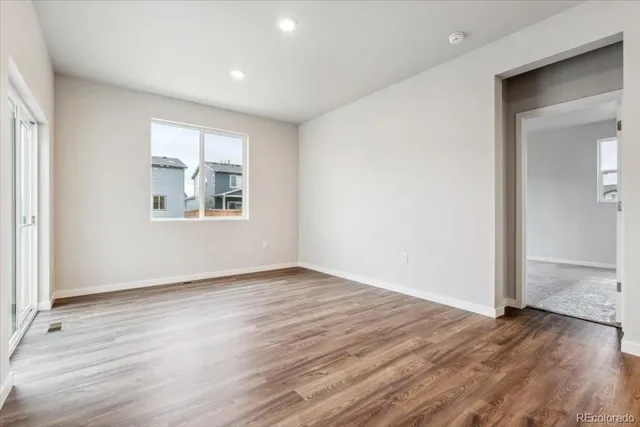 an empty room with wooden floor and windows