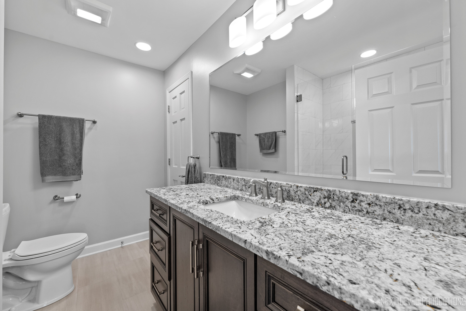 479 River Bend Road, Unit 111 Naperville, IL 60540 - Photo 16 of 25 a bathroom with a granite countertop sink a toilet and mirror